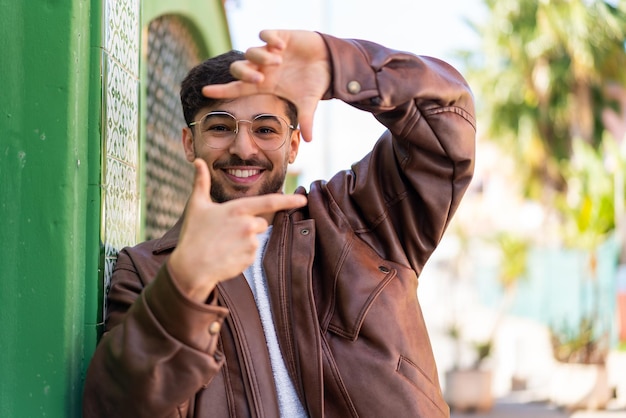 Handsome Arab man at outdoors focusing face Framing symbol