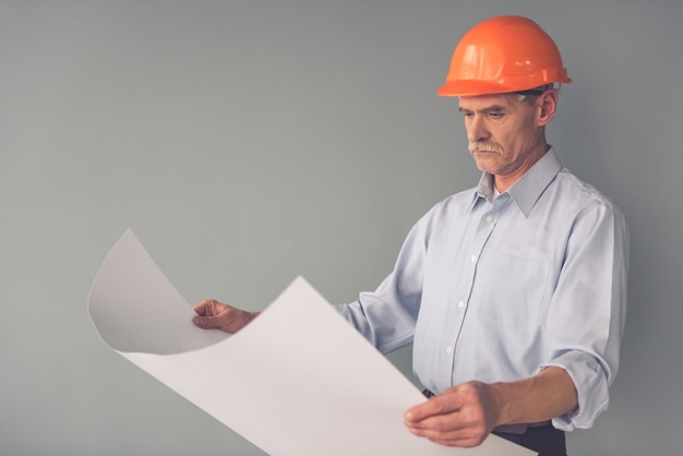 Handsome architect in protective helmet is studying drafts