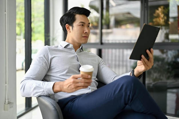 Handsome Asian businessman sipping coffee in an office lounge