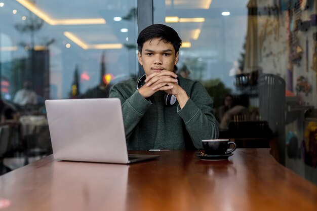 Handsome Asian male college student studying using a laptop at the cafe or coffee shop