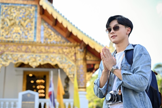 Handsome Asian male traveler standing and putting his hands together in a prayer position