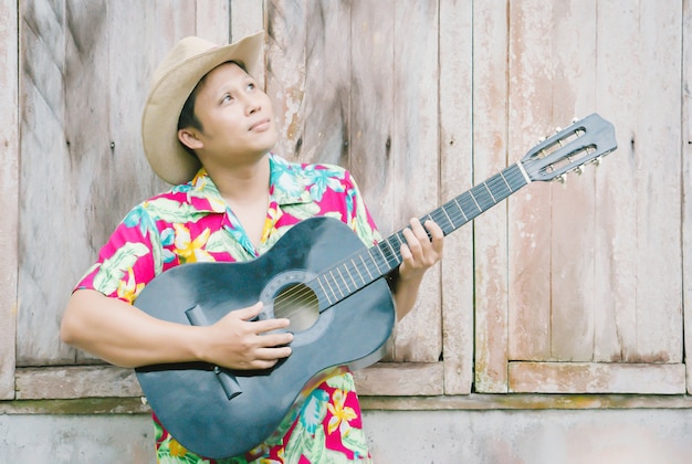 Handsome Asian male wearing  summer clothes playing acoustic guitar at relax time 