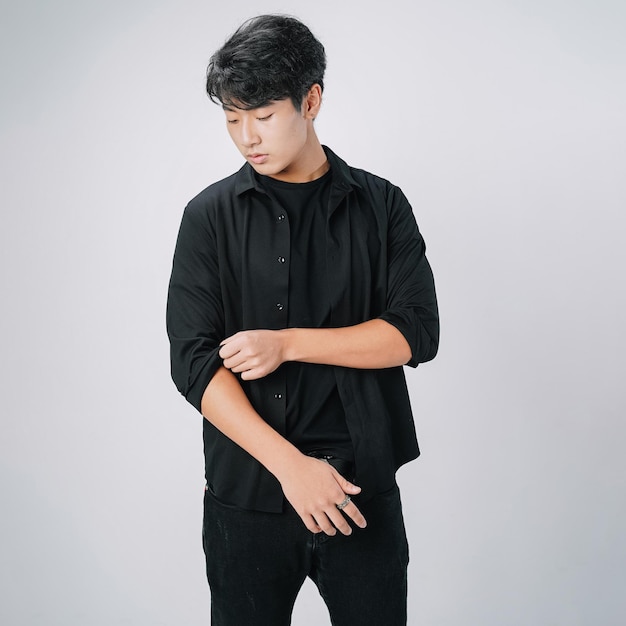 Handsome asian man fixing sleeves standing isolated gray wall