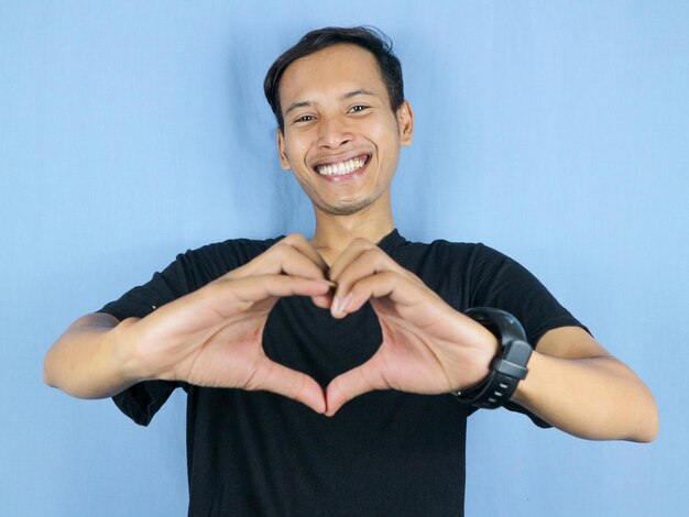 Photo handsome asian man is making a heart shape symbol with his fingers love and romantic concept