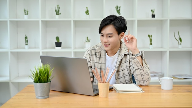 Handsome Asian man using laptop looking at laptop screen