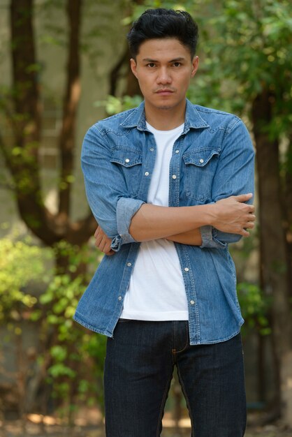 Handsome Asian man with arms crossed at the park outdoors