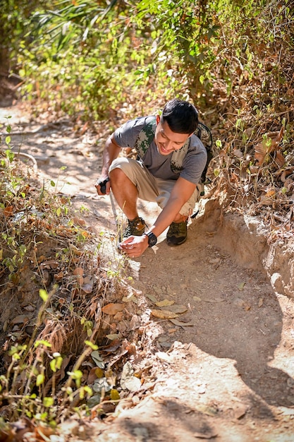 Handsome Asian man with trekking gear trekking at the rocky mountain trail on sunny day