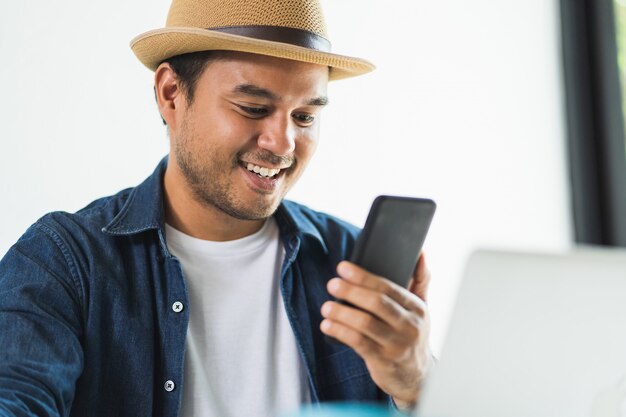 Handsome Asian man working from home with smartphone