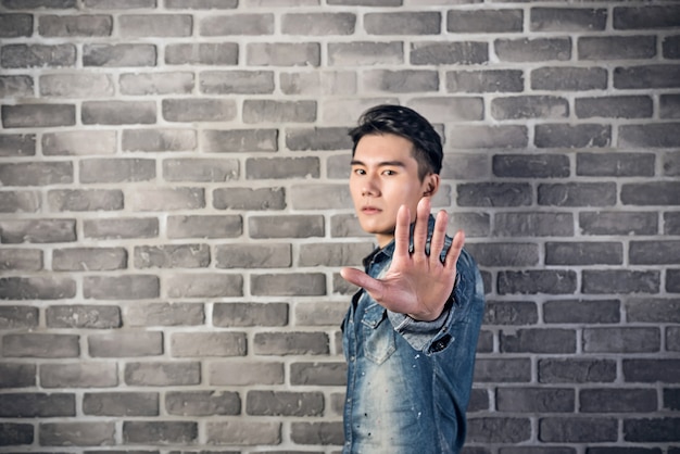 Handsome Asian young man against the gray brick wall