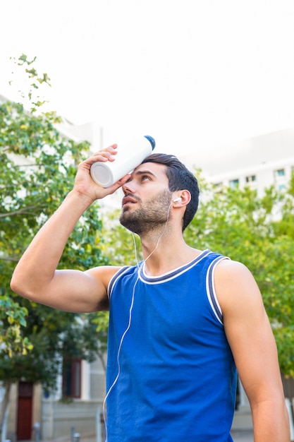 Handsome athlete cooling his forehead with bottle