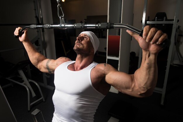 Handsome Athlete Doing Heavy Weight Exercise For Back On Machine