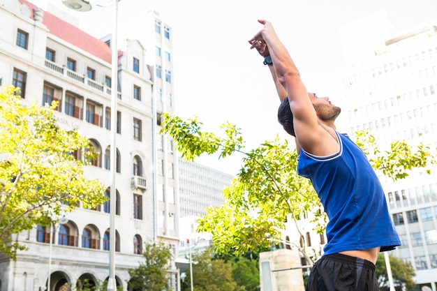 Handsome athlete stretching in front of buildings