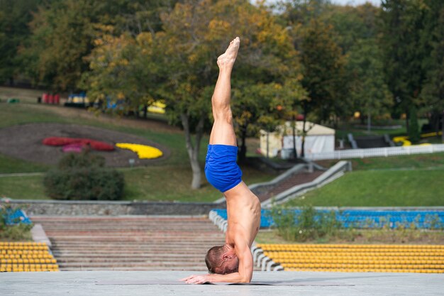 Handsome Athletic man doing yoga asanas in the park