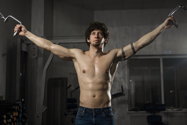 Handsome athletic man trains his chest in the gym Male fitness