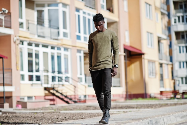 Handsome and attractive african american man posing next to the tall building on a street