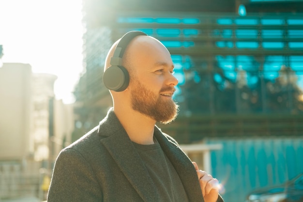 Handsome bald bearded man walks in the sunlight while wearing headset