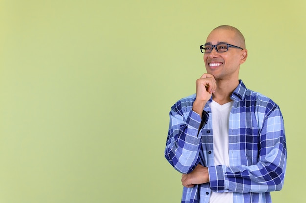  handsome bald hipster man with mixed race against colored wall