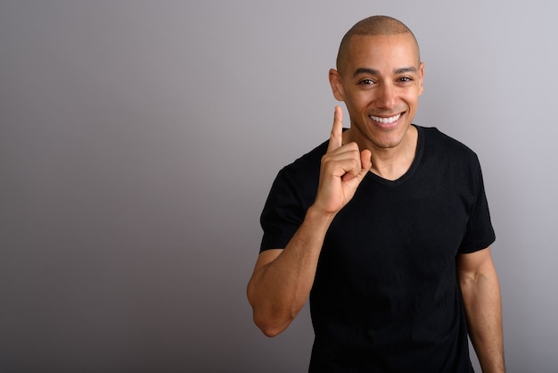 handsome bald man wearing black shirt on gray