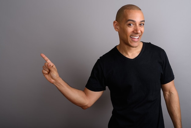 handsome bald man wearing black shirt on gray