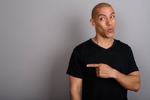 handsome bald man wearing black shirt on gray