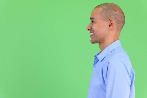 handsome bald multi ethnic businessman against green wall