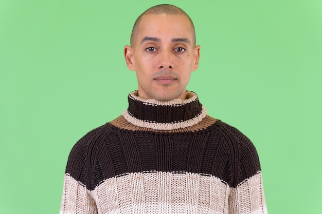  handsome bald multi ethnic man ready for winter against green wall