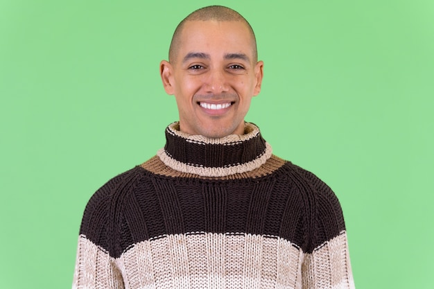  handsome bald multi ethnic man ready for winter against green wall