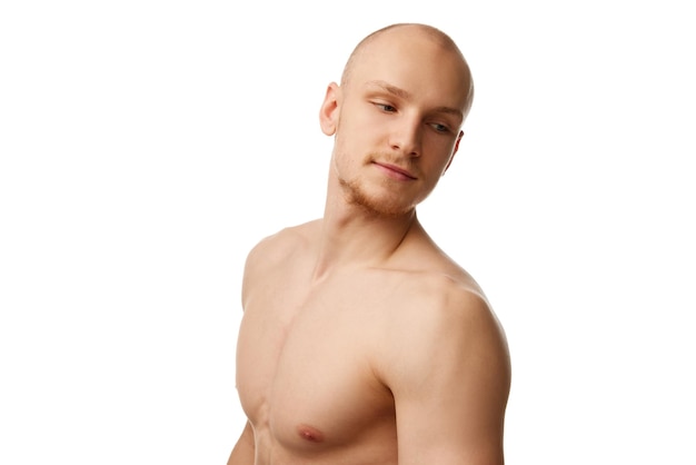 Handsome bald young guy with unshaved face muscular body standing shirtless isolated against white