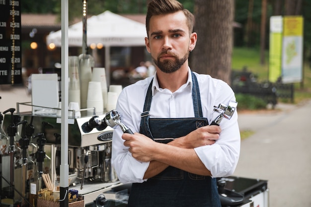 Handsome barista man during work in his movable street coffee shop