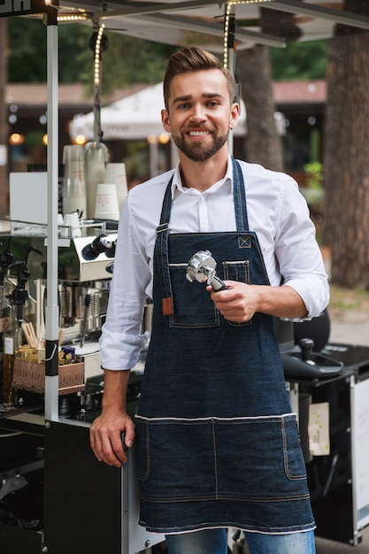 Handsome barista man during work in his movable street coffee shop