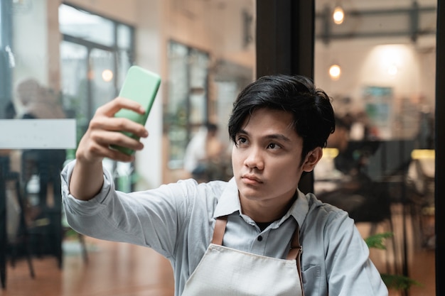 Handsome barista selfie use a smartphone camera at work breaks