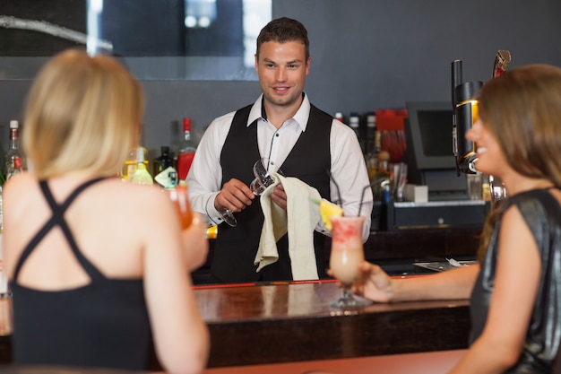 Handsome bartender working while gorgeous friends speaking