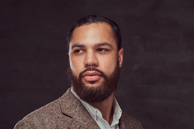 Handsome bearded African-American businessman in a brown classic jacket. Isolated on a dark background.