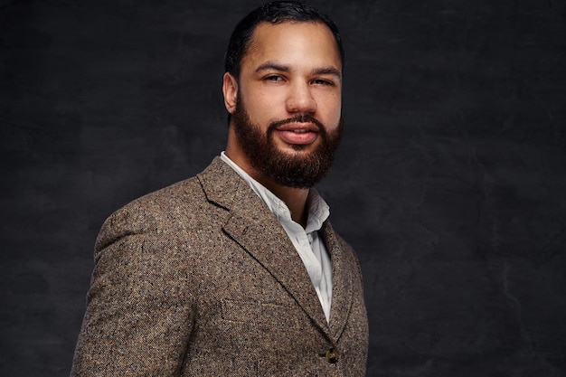 Handsome bearded African-American businessman in a brown classic jacket. Isolated on a dark background.