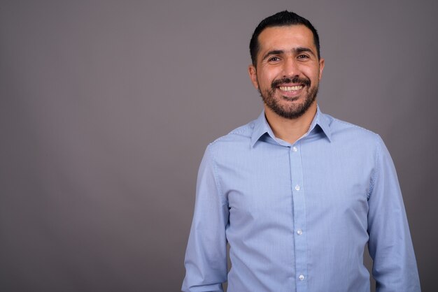 Handsome bearded businessman against gray wall