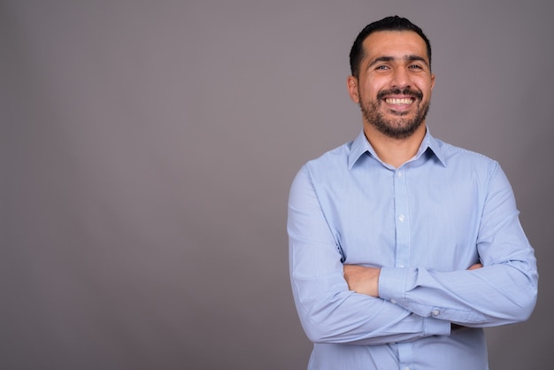 Handsome bearded businessman against gray wall