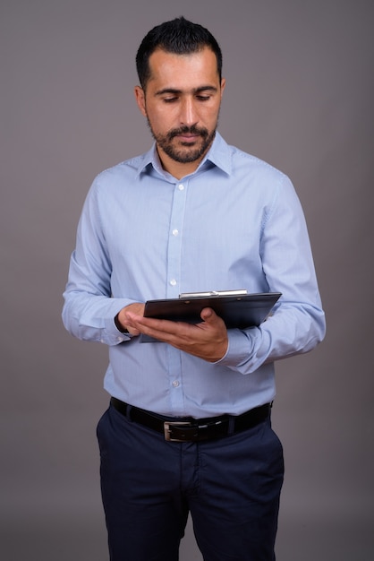 Handsome bearded businessman against gray wall