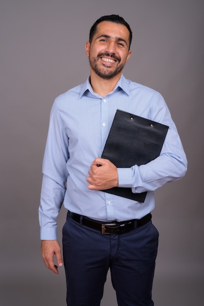 Handsome bearded businessman against gray wall