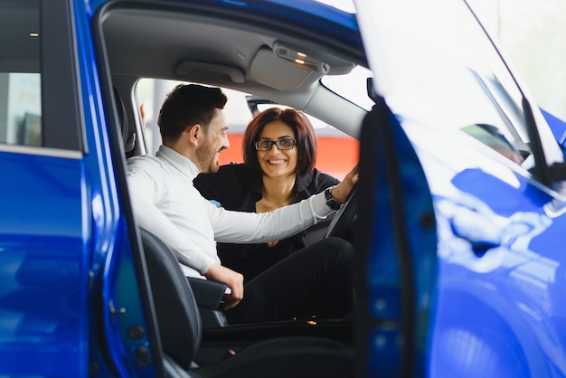 Handsome bearded businessman is sitting in a new car in car dealership