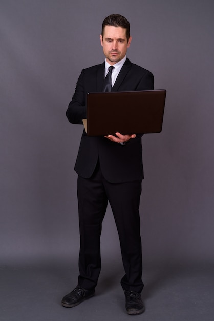 handsome bearded businessman in suit against gray wall