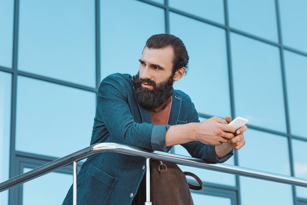 Handsome bearded businessman using smartphone outdoors