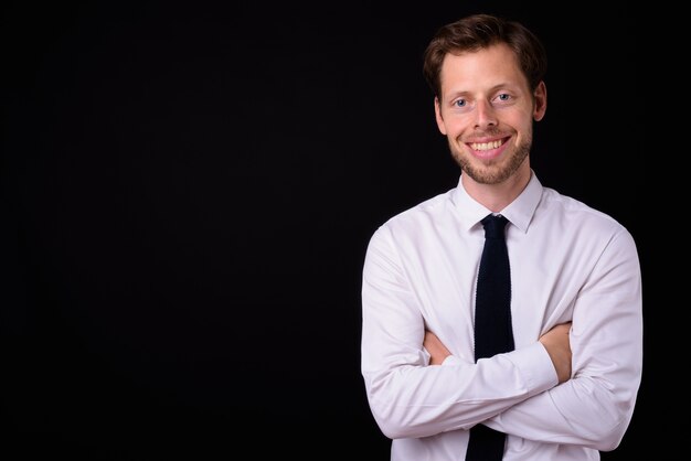 handsome bearded businessman with brown hair against black space