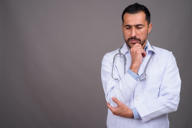 Handsome bearded doctor against gray wall