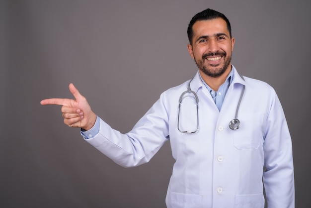 Handsome bearded doctor against gray wall