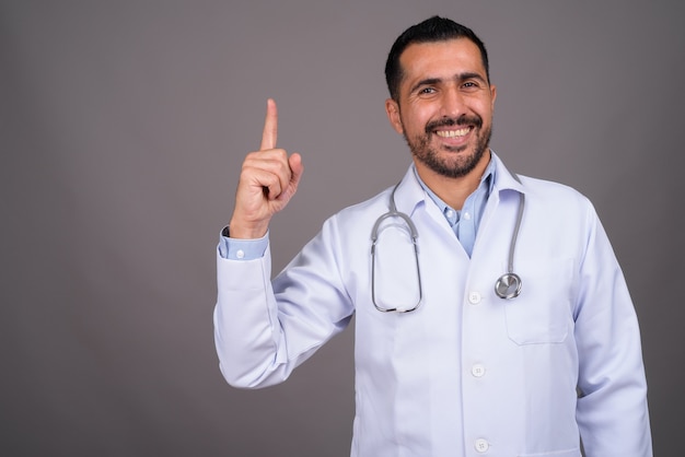 Handsome bearded doctor against gray wall