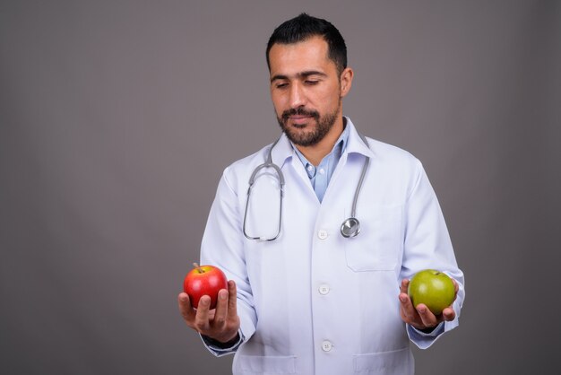 Handsome bearded doctor against gray wall