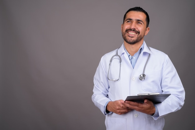 Handsome bearded doctor against gray wall