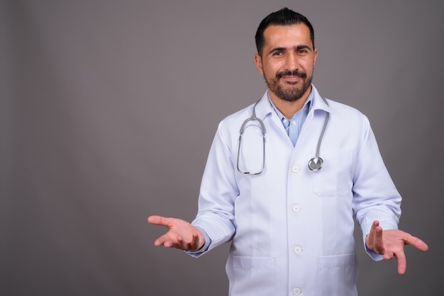 Handsome bearded doctor against gray wall