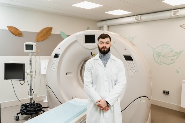 Handsome bearded doctor in medical robe with computed tomograph for obtain detailed internal images of the body of patient Man doctor in CT scan computed tomography room in medical clinic