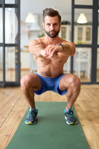 Handsome bearded gentleman with perfect body looking at camera and smiling while doing exercise